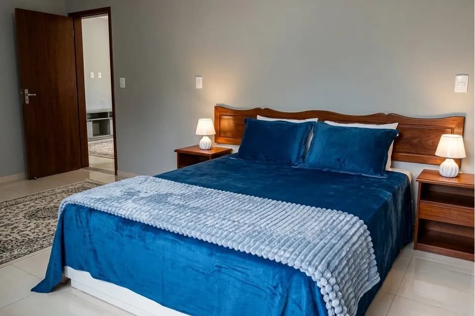 Cama de casal da Suíte Araucária, com roupa de cama azul e manta cinza